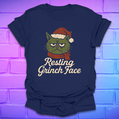 Navy blue t-shirt with a Grinch face cat graphic and 'Resting Grinch Face' text on a brick wall background.