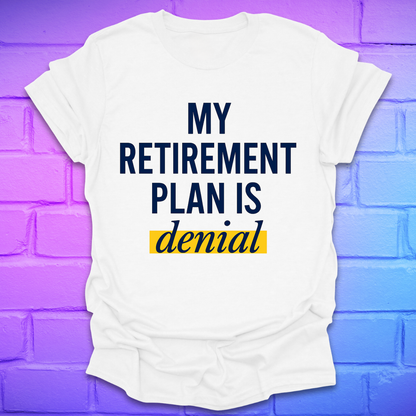 White t-shirt with 'My Retirement Plan is Denial' text on a purple brick wall background