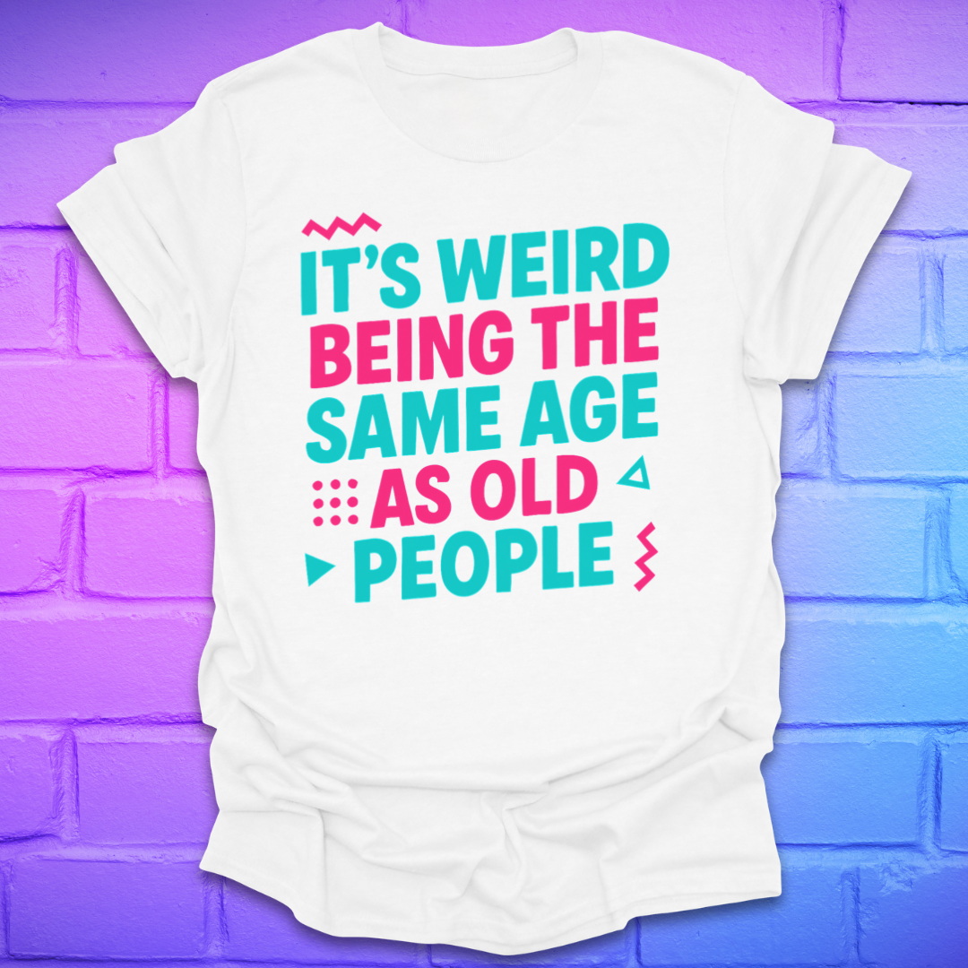White t-shirt with colorful text, 'it's weird being the same age as old people' on a brick wall background