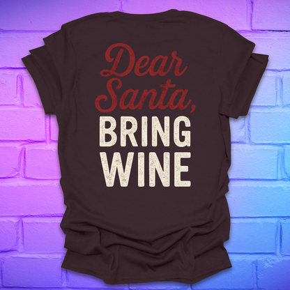 Brown t-shirt with 'Dear Santa, Bring Wine' text on the back, on a brick wall background