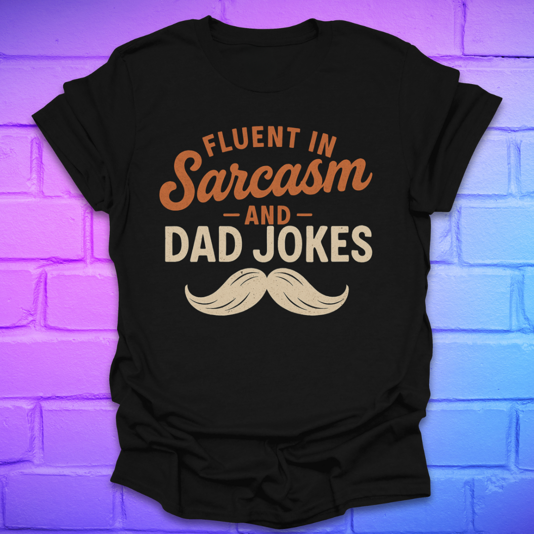 Black t-shirt with 'Fluent in Sarcasm and Dad Jokes' text and mustache graphic on a brick wall background.