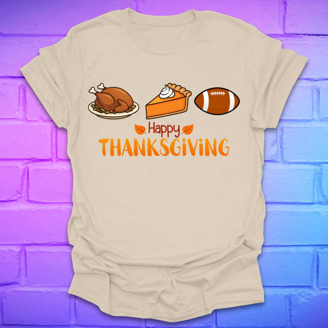 Beige t-shirt with thanksgiving theme and text, 'happy thanksgiving' with turkey, pie and football, on a brick background.