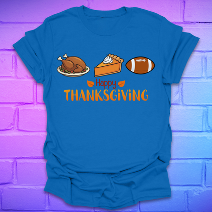 Royal blue t-shirt with thanksgiving theme and text, 'happy thanksgiving' with turkey, pie and football, on a brick background.