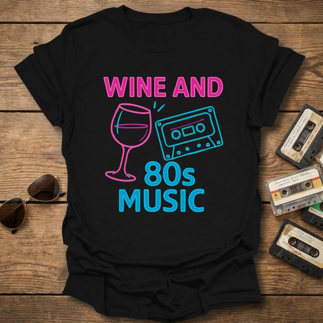 Black t-shirt with 'Wine and 80s Music' design on a wooden surface with cassettes and sunglasses.