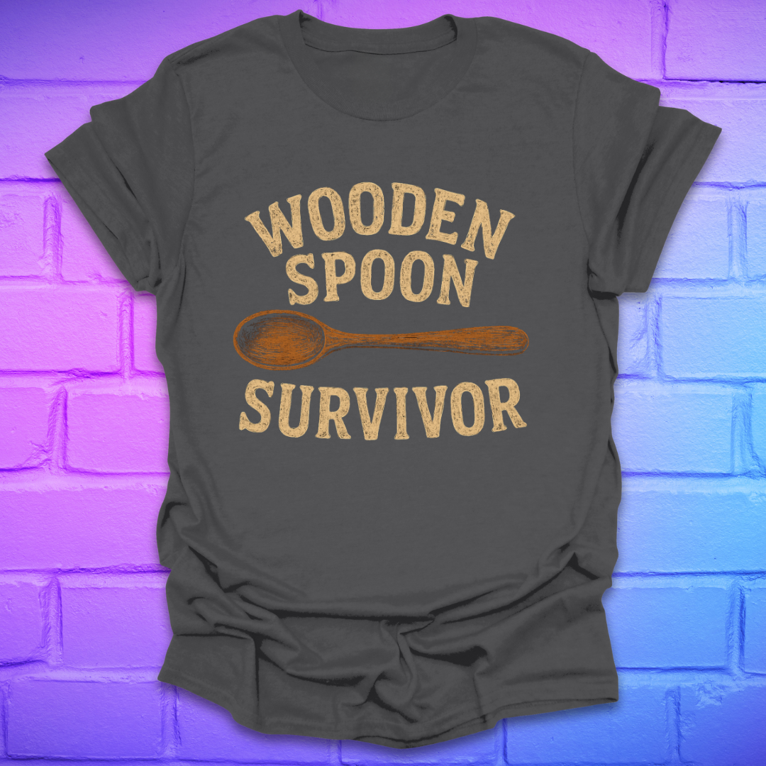 Gray t-shirt with 'Wooden Spoon Survivor' text and wooden spoon graphic on a brick wall background