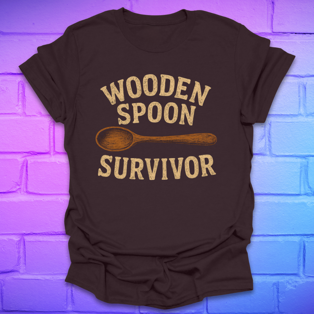 Brown t-shirt with 'Wooden Spoon Survivor' text and spoon graphic on a brick wall background