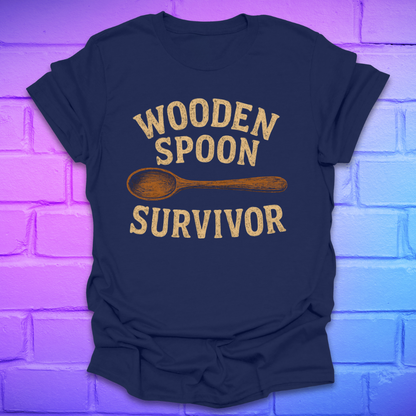 Navy blue t-shirt with 'Wooden Spoon Survivor' text and wooden spoon graphic on a brick wall background.