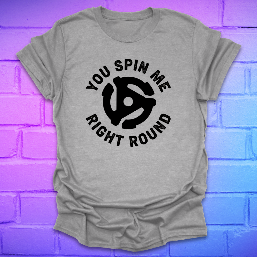 Grey t-shirt with black graphic and text ,'you spin me right round' on a purple brick wall background